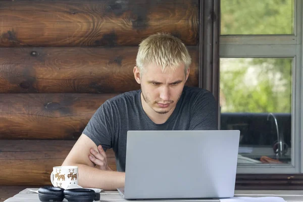 De man concentreert zich op het werken met een laptop, zittend op het terras van een landhuis Rechtenvrije Stockafbeeldingen