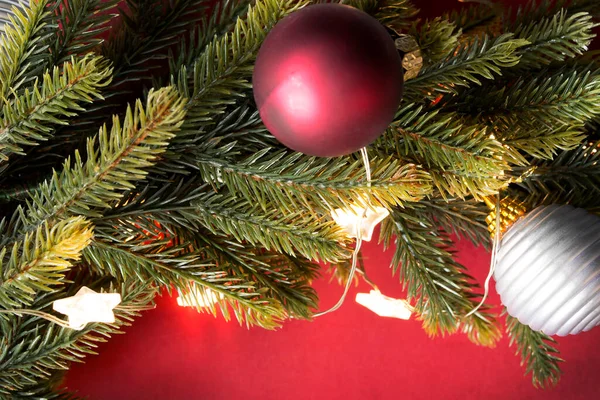 Weihnachtsbaum Zweig Mit Kugeln Und Lichtern Nahaufnahme Auf Rotem Hintergrund — Stockfoto