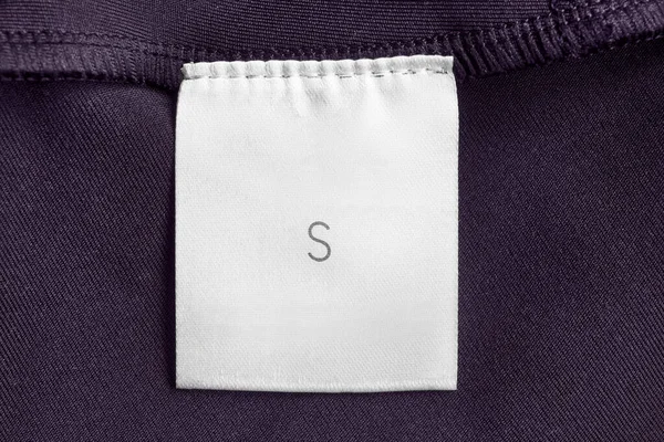 サイズS服ラベル上紫のテキスタイル背景クローズアップ — ストック写真
