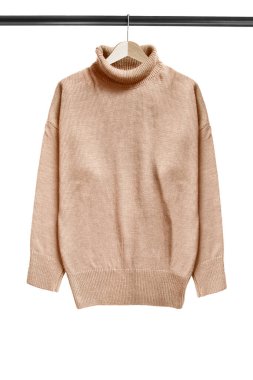 Beyazların üzerine izole edilmiş ahşap elbise askılarında asılı bej rengi süveter.