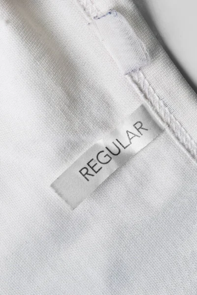 Etiqueta Ropa Dice Regular Sobre Fondo Textil Blanco — Foto de Stock