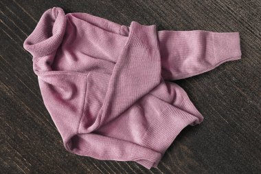 Koyu kahverengi ahşap arka planda pembe örgü süveter