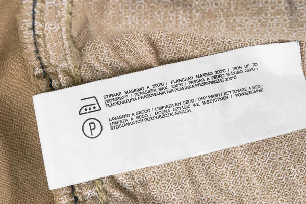 Instrucciones Cuidado Etiqueta Ropa Diferentes Idiomas Sobre Fondo Textil Beige — Foto de Stock