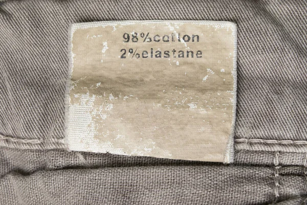 Fabric composition clothing label on textile background closeup