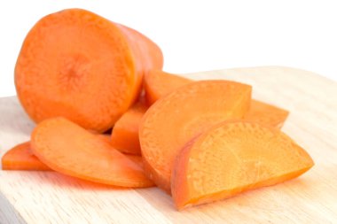 Kesme tahtasındaki havuç dilimi beyaz arkaplanda izole edilmiş.