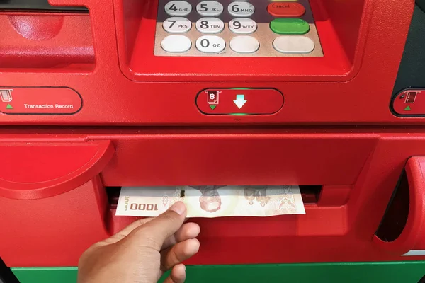 Hand receiving money from the ATM machine.