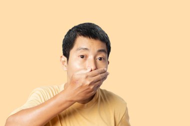 Genç Asyalı adam sarı arka planda izole edilmiş, şok olmuş ve şaşırmış. kırpma yolları.