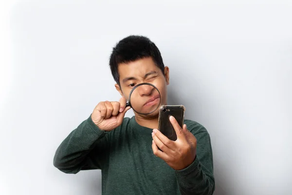 Ung Man Tittar Genom Förstoringsglas Smartphone Grå Bakgrund — Stockfoto