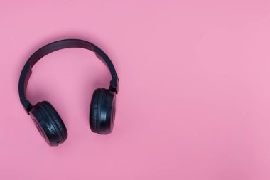 Pembe arka planda fotokopi alanı olan siyah kulaklıklar. Müzik konsepti.