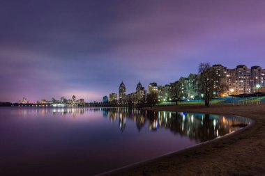 Ukrayna, Kiev 'in Obolon bölgesindeki modern binaların gece manzarası, Dinyeper Nehri' ne yakın olan ışıklar sakin suları yansıtıyor..
