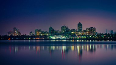 Ukrayna, Kiev 'in Obolon bölgesindeki modern binaların gece manzarası, Dinyeper Nehri' ne yakın olan ışıklar sakin suları yansıtıyor..