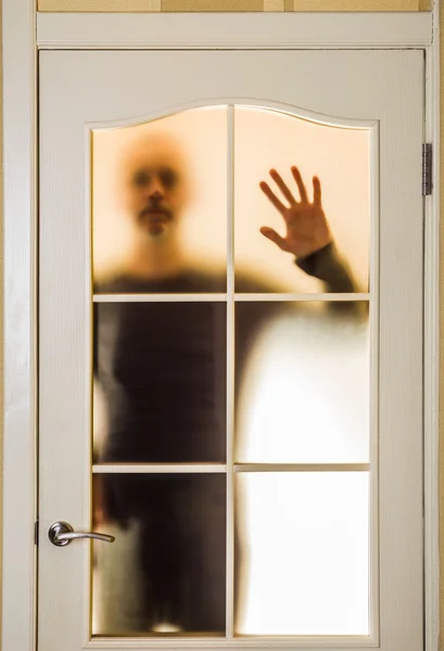 Человек за стеклянной дверью — стоковое фото