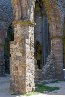 The Abbey of Saint-Mathieu de Fine-Terre, in Brittany, France. Sunlit Gothic ruin interior reveals towering arches and weathered stone columns.