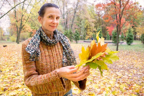 Donna che raccoglie foglie in autunno — Foto Stock