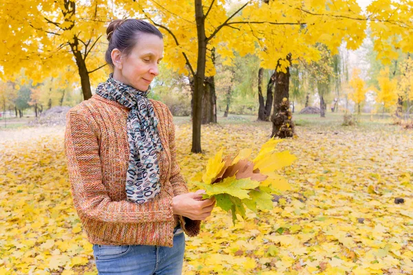 Kobieta zbieranie liści jesienią — Zdjęcie stockowe