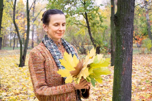 Женщина собирает листья осенью — стоковое фото