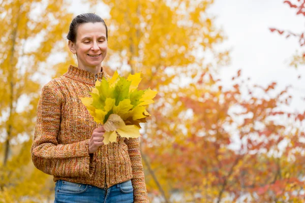 Donna che raccoglie foglie in autunno — Foto Stock