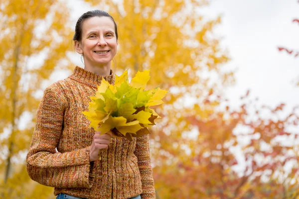 Frau pflückt Blätter im Herbst — Stockfoto