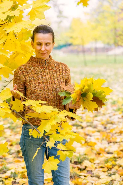 Kobieta zbieranie liści jesienią — Zdjęcie stockowe