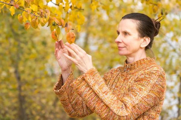 Frau pflückt Blätter im Herbst — Stockfoto