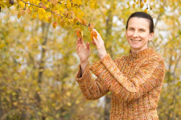 Donna che raccoglie foglie in autunno — Foto Stock