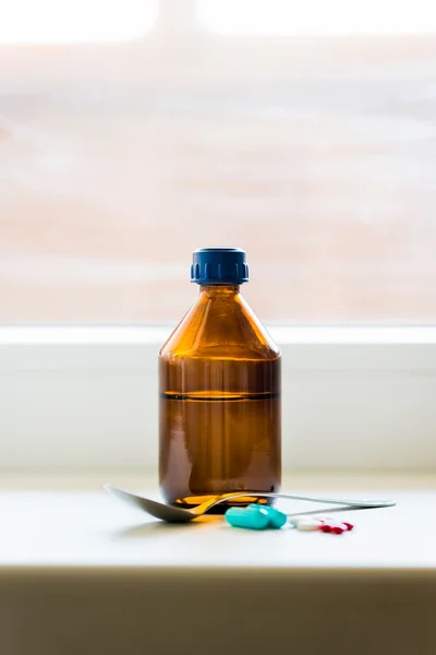 Hostmedicin flaska med sked nära fönstret — Stockfoto