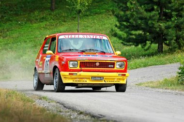 Unidentified drivers on a yello and red vintage Fiat 127 racing car