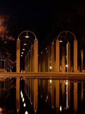 Yağmurdan sonra gece sahneleri - fener ışıkları ve su birikintisi. Bir yerleşim bölgesinde yürüyüş yolu.
