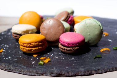 Limonlar ve portakal kabukları süslemek için koyu gri bir levhada farklı türde badem kurabiyesi.