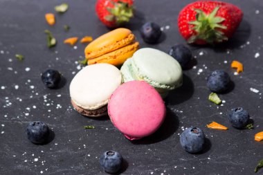 Limon ve portakal kabukları süs ve meyve olarak koyu gri bir levhada farklı türde badem kurabiyesi. 