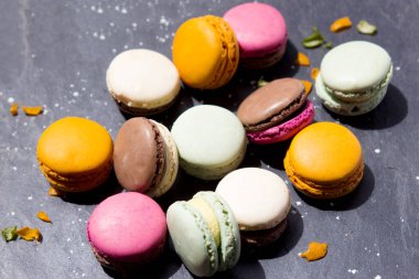 Limonlar ve portakal kabukları süslemek için koyu gri bir levhada farklı türde badem kurabiyesi.