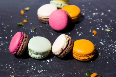 Limonlar ve portakal kabukları süslemek için koyu gri bir levhada farklı türde badem kurabiyesi.