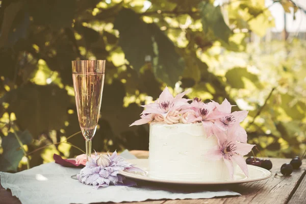 Gâteau crémeux aux fleurs clématites sur la table en bois — Photo