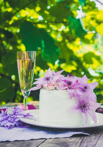 Pastel cremoso con flores de clematis en la mesa de madera — Foto de Stock