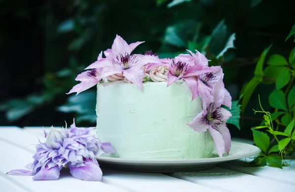 Romige taart met clematis bloemen op de houten tafel — Stockfoto