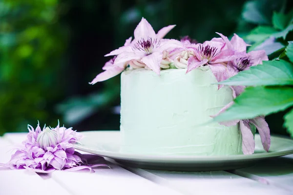 Pastel cremoso con flores de clematis en la mesa de madera — Foto de Stock