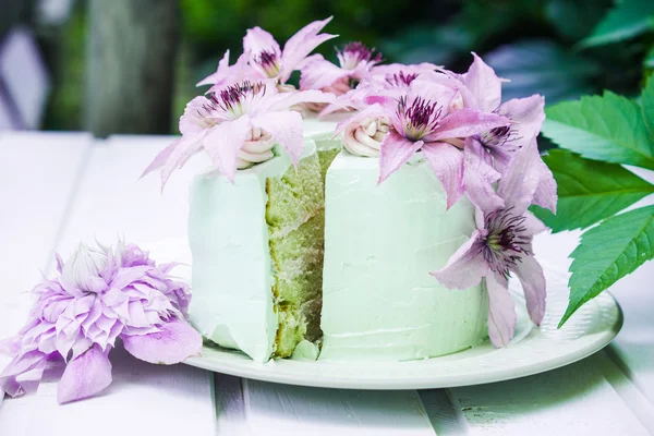 Pastel cremoso con flores de clematis en la mesa de madera — Foto de Stock