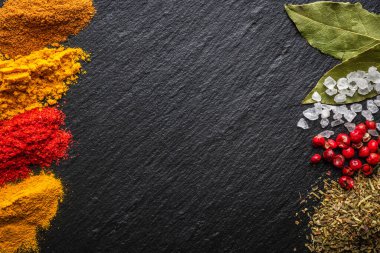 Siyah taş arka planda parlak ve renkli baharatlar. Arkaplan için farklı baharatlar ve otlar.