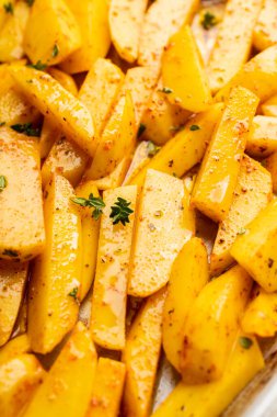 Tavada baharat ve bitkilerle dilimlenmiş çiğ patates pişirmeye hazır. Seçici odaklanma. Sığ alan derinliği.