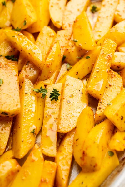 Tavada baharat ve bitkilerle dilimlenmiş çiğ patates pişirmeye hazır. Seçici odaklanma. Sığ alan derinliği.