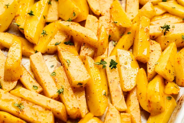 Tavada baharat ve bitkilerle dilimlenmiş çiğ patates pişirmeye hazır. Seçici odaklanma. Sığ alan derinliği.