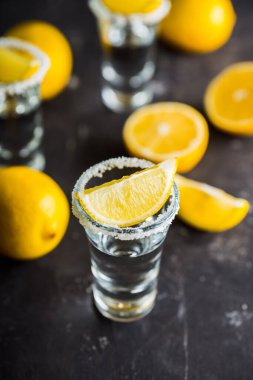 Koyu kırsal arka planda limon dilimli tekila. Seçici odaklanma. Sığ alan derinliği.