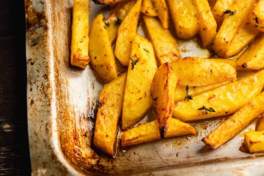 Sliced grilled potatoes with spices and herbs on the pan. Selective focus. Shallow depth of field. 