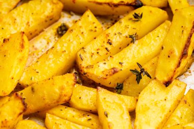 Sliced grilled potatoes with spices and herbs on the pan. Selective focus. Shallow depth of field. 