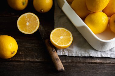 Ripe bright lemons in white bowl on the dark rustic background. Selective focus. Shallow depth of field. 