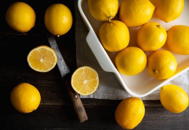 Ripe bright lemons in white bowl on the dark rustic background. Selective focus. Shallow depth of field. 