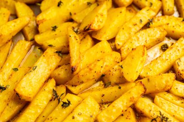Sliced grilled potatoes with spices and herbs on the pan. Selective focus. Shallow depth of field.