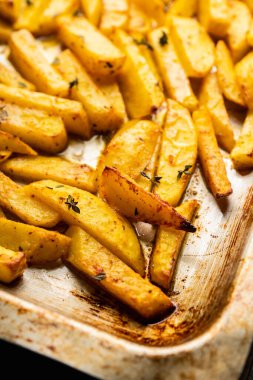 Sliced grilled potatoes with spices and herbs on the pan. Selective focus. Shallow depth of field.
