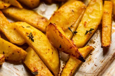 Sliced grilled potatoes with spices and herbs on the pan. Selective focus. Shallow depth of field.