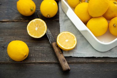 Ripe bright lemons in white bowl on the dark rustic background. Selective focus. Shallow depth of field.